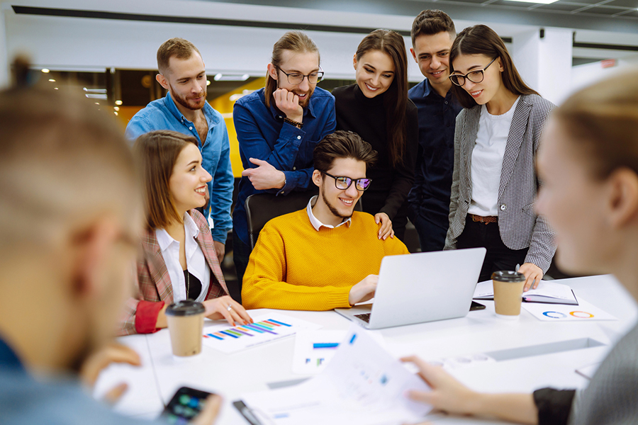 A team of young professionals collaborating on Performance Marketing Analytics, gathered around a laptop in a modern office setting