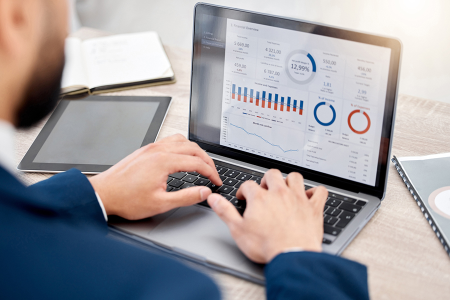 Business professional analyzing advertising analytics on a laptop screen, displaying financial charts, graphs, and performance metrics