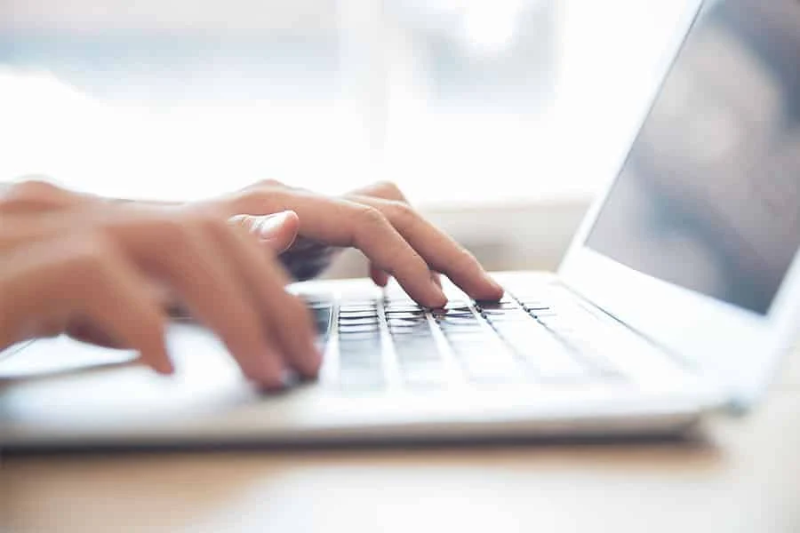 close up image of hands typing on laptop concept image of what is ad copywriting.