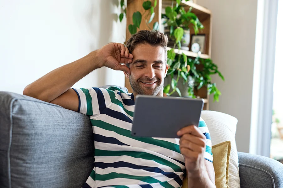 Consumer Sitting On A Couch At Home Engaging With A Streaming Tv Ad On A Mobile Device consumer sitting on a couch at home engaging with a streaming tv ad on a mobile device