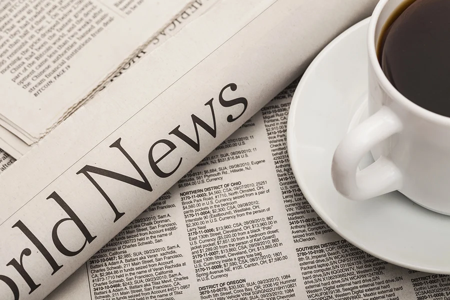 folded newspaper with 'world news' headline beside a cup of coffee, highlighting the relevance of news media advertising