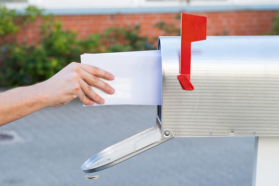 Hand removing envelopes from a mailbox, representing direct mail ads as an effective marketing strategy for reaching targeted audiences