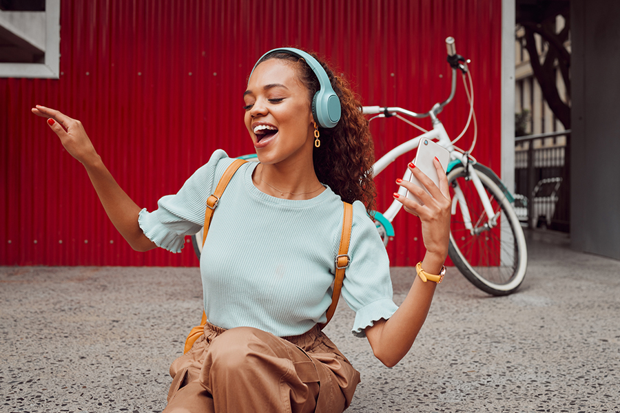 Happy young woman enjoying music on wireless headphones, showcasing the impact of digital audio marketing on listener engagement