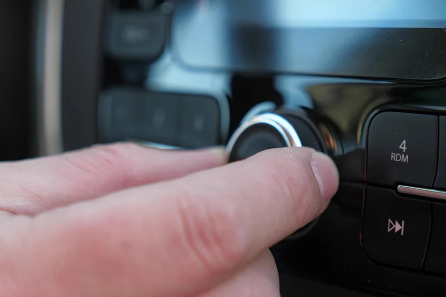person adjusting the car radio while tuned to an fm station, showcasing the continued relevance of traditional radio advertising