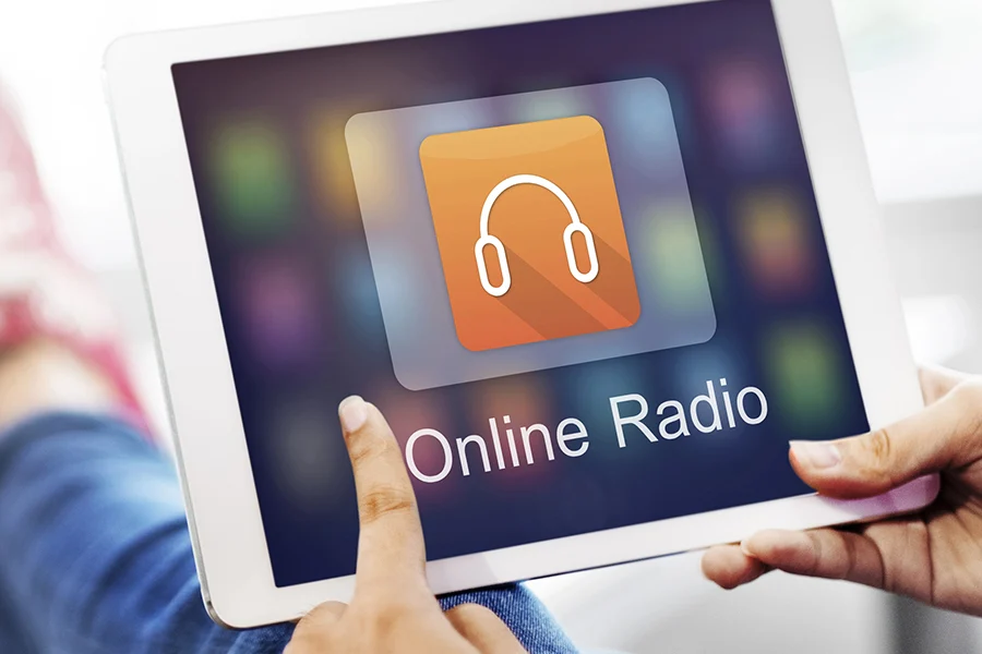 person holding a tablet displaying an 'online radio' app icon, representing streaming audio advertising opportunities