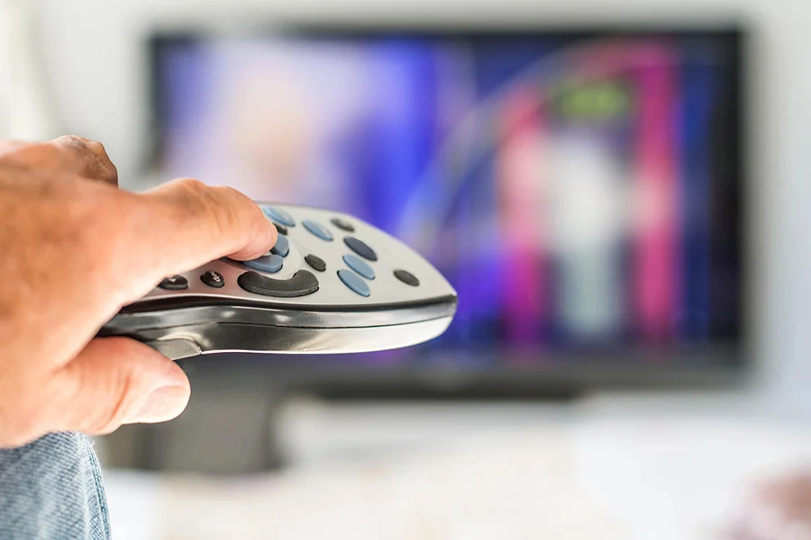 Person Using A Remote Control To Browse Cable Tv Advertising Content On A Television Screen person using a remote control to browse cable tv advertising content on a television screen