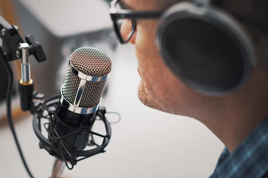 radio host speaking into a professional microphone while wearing headphones, illustrating the impact of amfm radio advertising