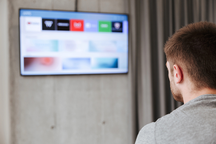 Selective focus of a man watching on a smart TV illustrating the power of network broadcast media advertising