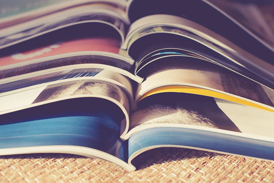 stack of open magazines showcasing high-quality print layouts, emphasizing advertising costs in magazines and brand visibility