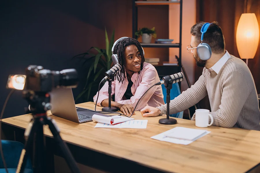 two podcast hosts in a recording studio discussing content, representing podcast audio advertising and branded sponsorship opportunities