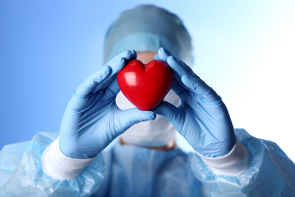 Cardiologist in scrubs holding up a heart figurine to showcase link building for cardiologists.