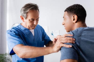 A chiropractor massaging a patient's shoulder