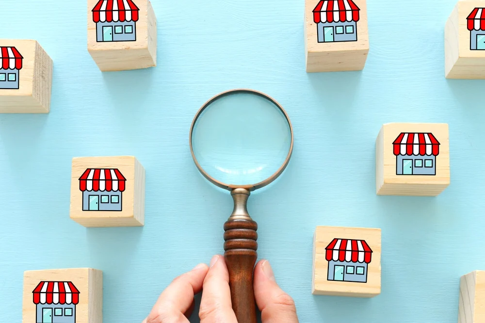 Person Choosing Wooden Cube With Store Sign. Concept Of Choosing Brand Over Others concept image for local franchise marketing and what works in local franchise marketing