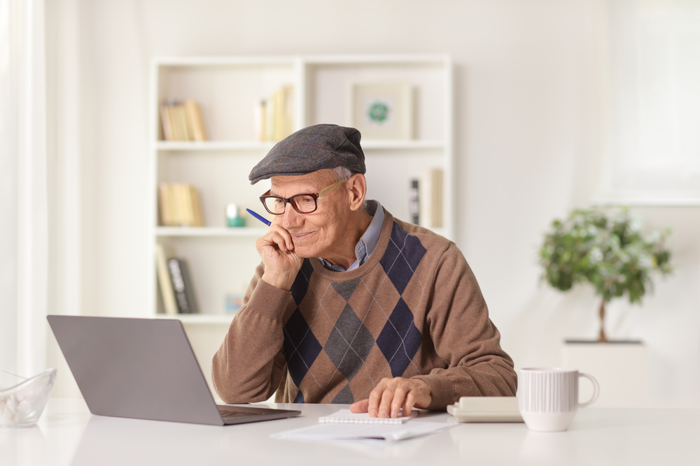 Elderly man using a laptop to search for senior living communities.