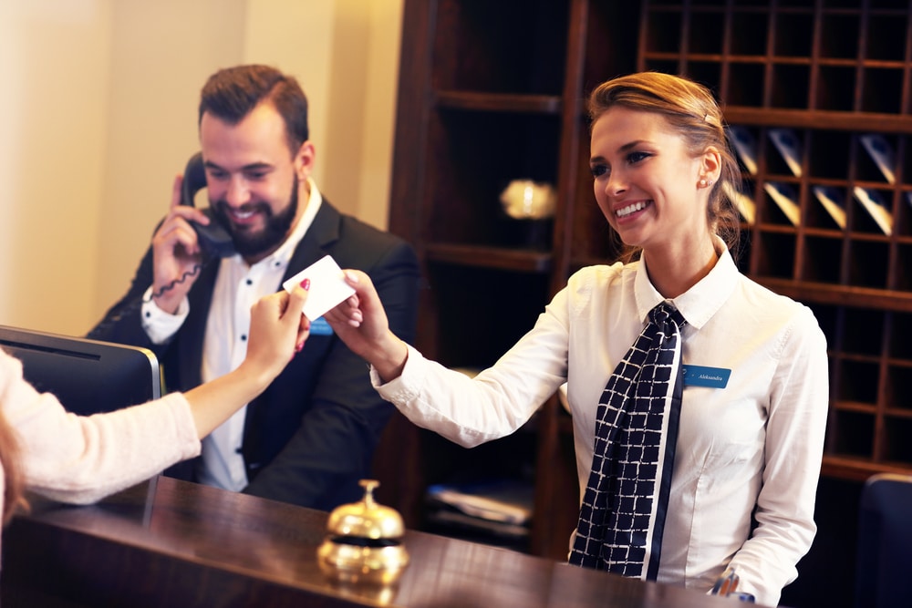 female hotel receptionist accepting customers credit card as payment