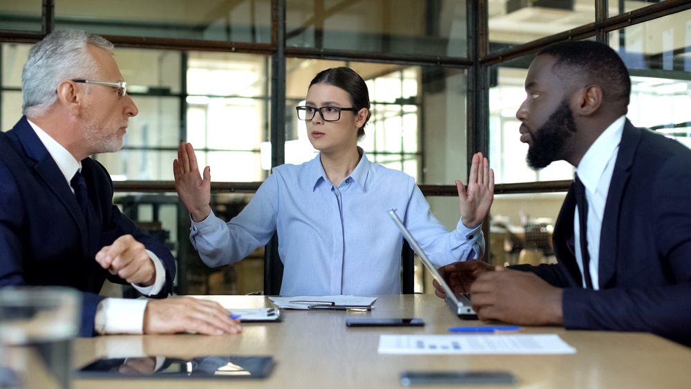 female team member resolving conflict between two men in suits