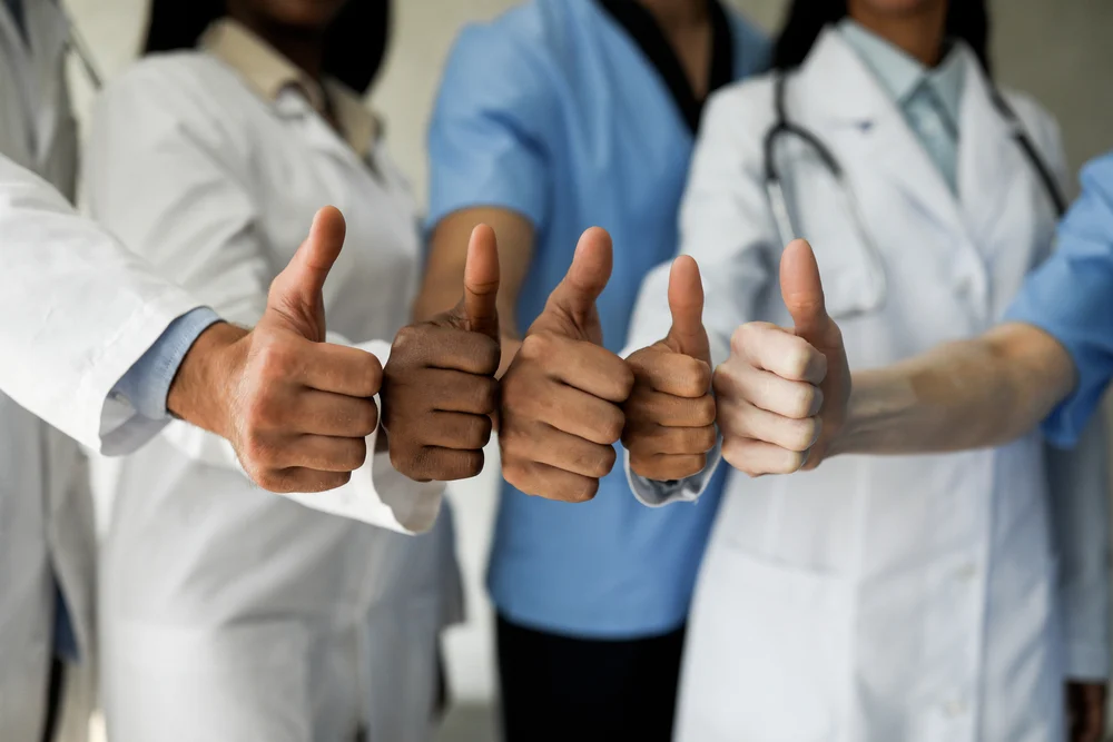 Unrecognizable Multiracial Group Of Doctors Showing Thumb Ups team of medical professionals using google business profile for healthcare service promotion