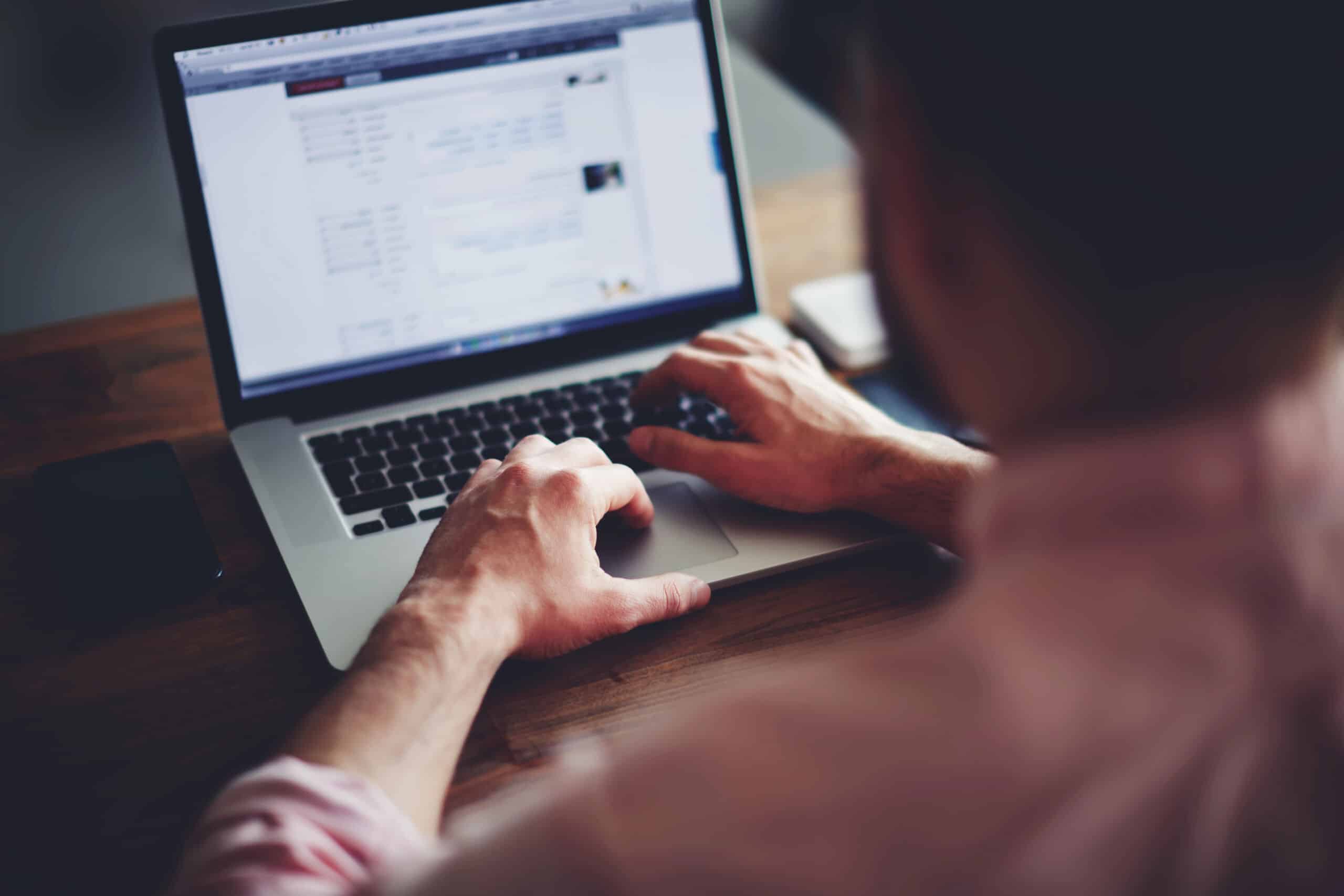 a man in the foreground looks at a blurred computer screen showing a performance report from a healthcare ppc case study