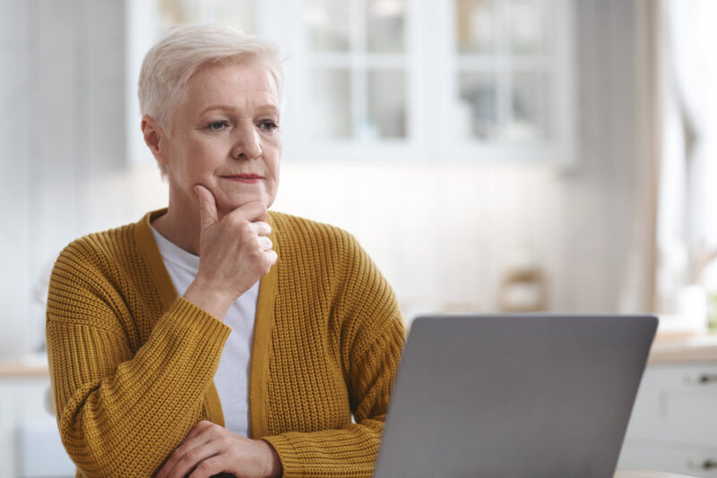 senior woman looking at assisted living site on laptop