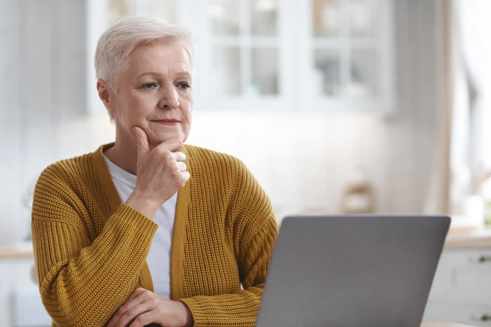 Senior-Woman-Looking-At-Assisted-Living-Site-On-Laptop woman looking at senior living options online