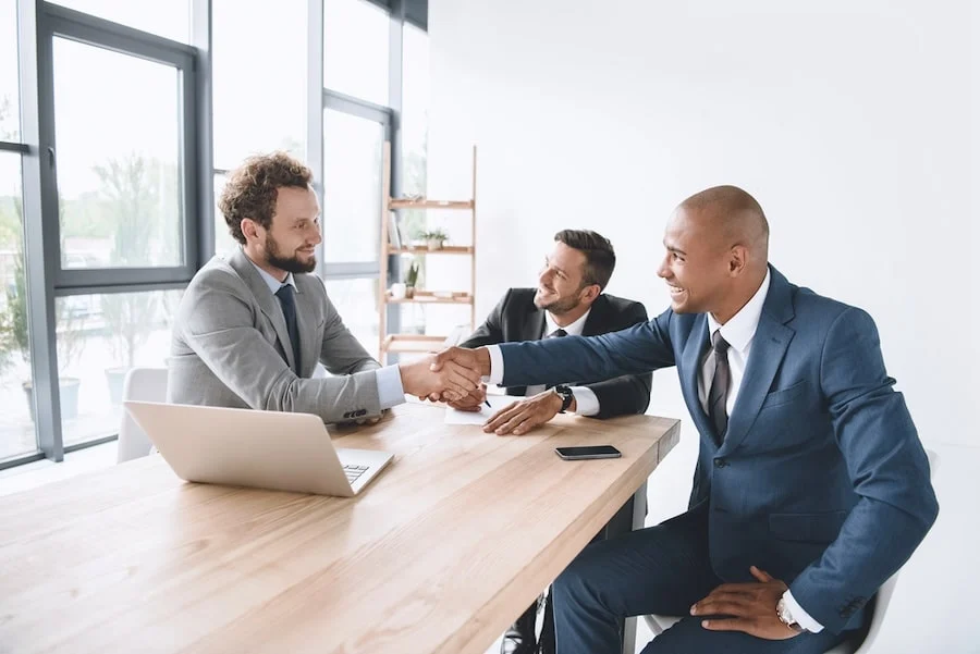 close-up of a handshake between business people with a bright office background, symbolizing a successful agreement
